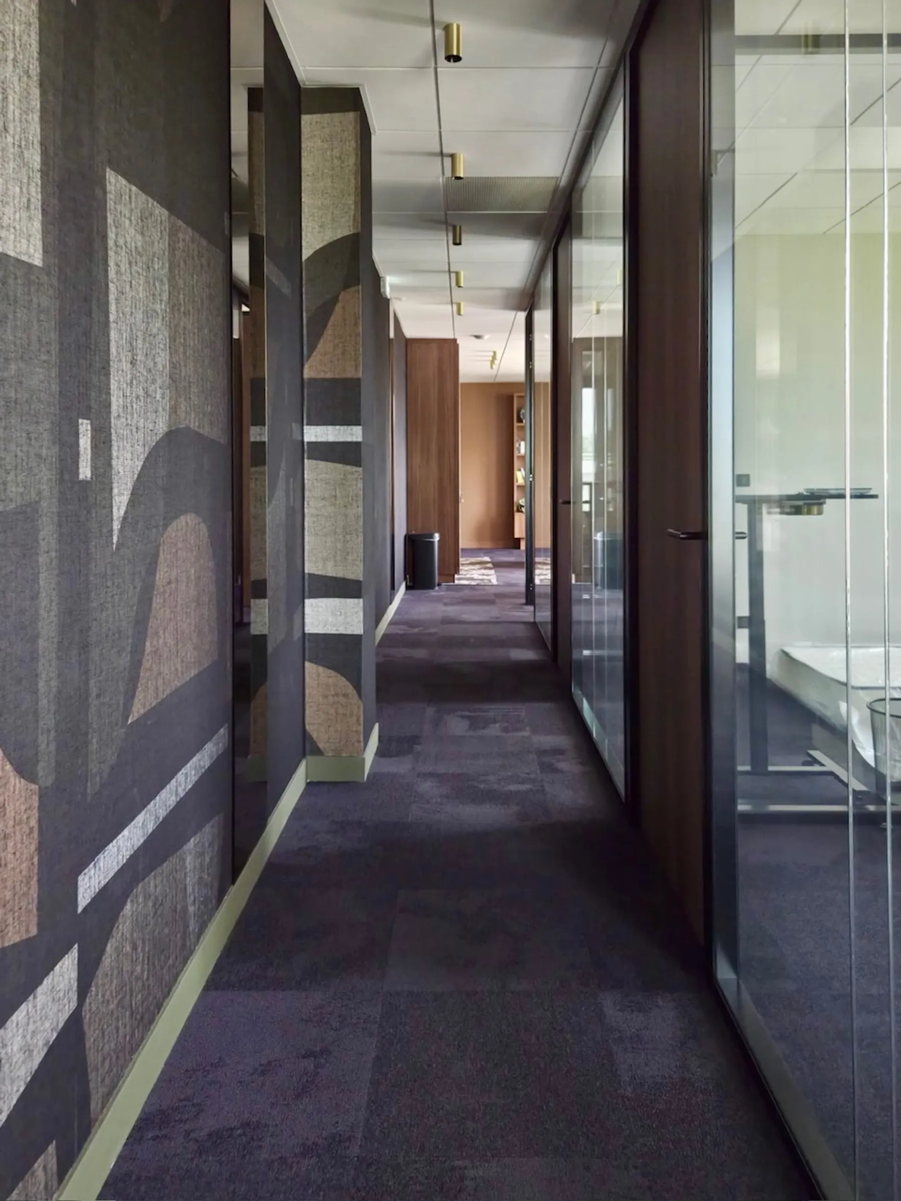 Couloir de bureaux haut de gamme entretenu, moquette et parois vitrées impeccables